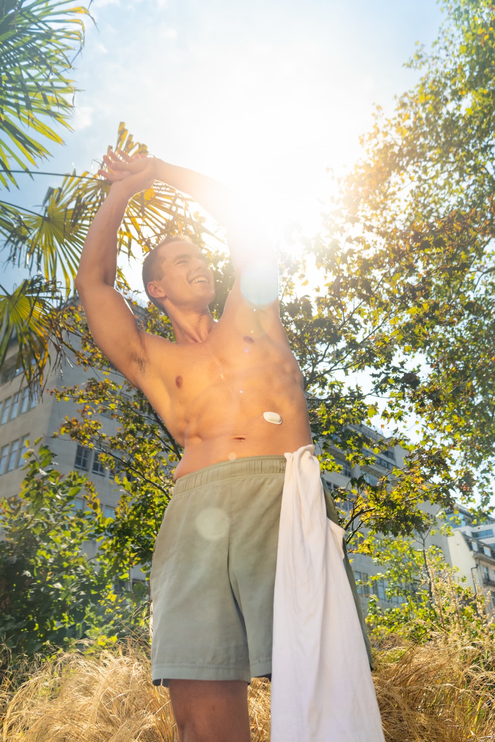 A model stretching in the sun with a towel over his shoulder, wearing the Suna device